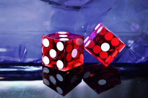Two red dice rest on a black, reflective surface
