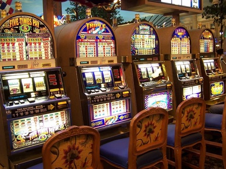 Five rustic looking casino slots machines with empty chairs in front of them