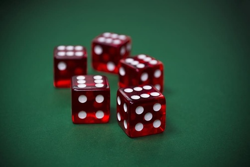 Five red dice set on a green casino baize