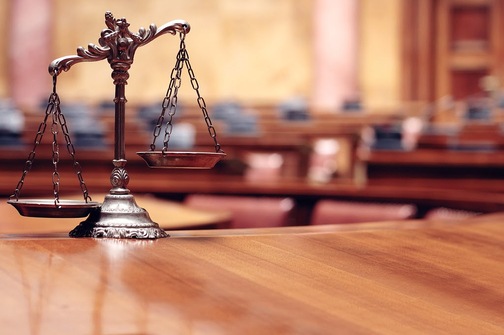 The scales of law rest on a wooden table in an empty courthouse