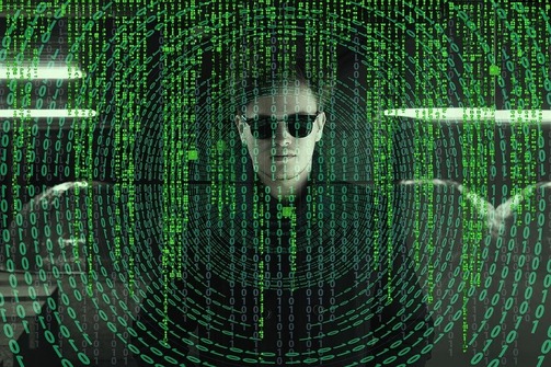 A Matrix-style image with a man in black sunglasses behind green computer code