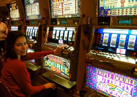 A lady with dark hair sits in front of a slot machine