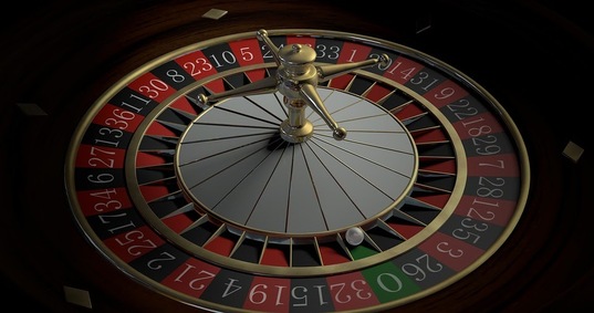 A casino roulette wheel with the white ball sitting in the green 0 section